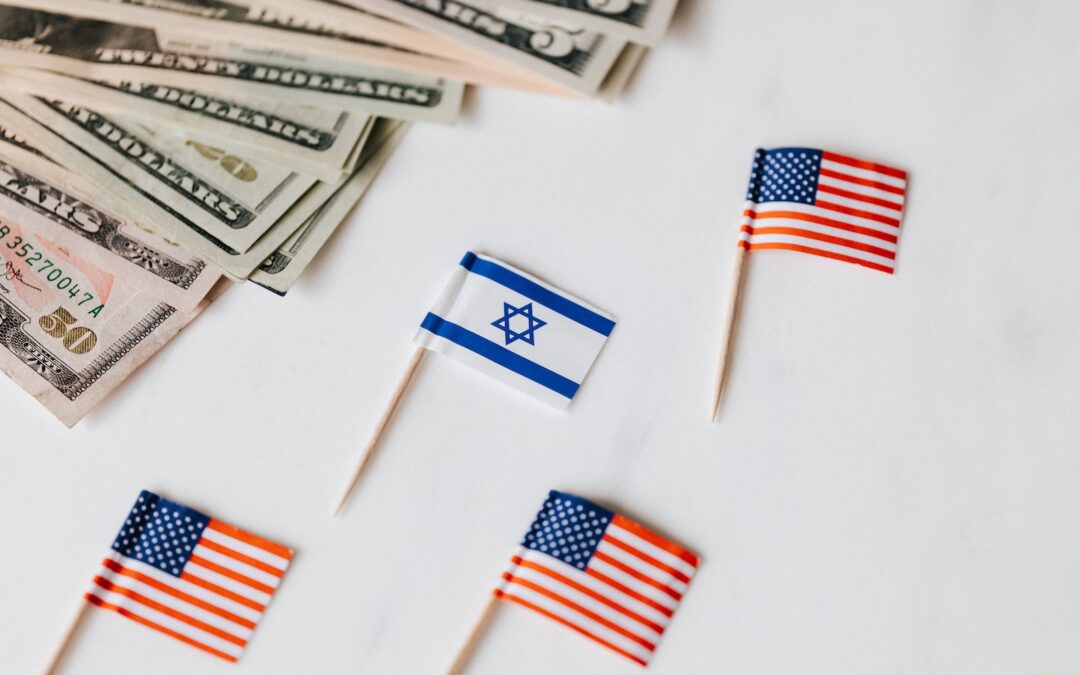 From above closeup of Israeli and American flags on toothpicks and different nominal pars of dollar banknotes on white background